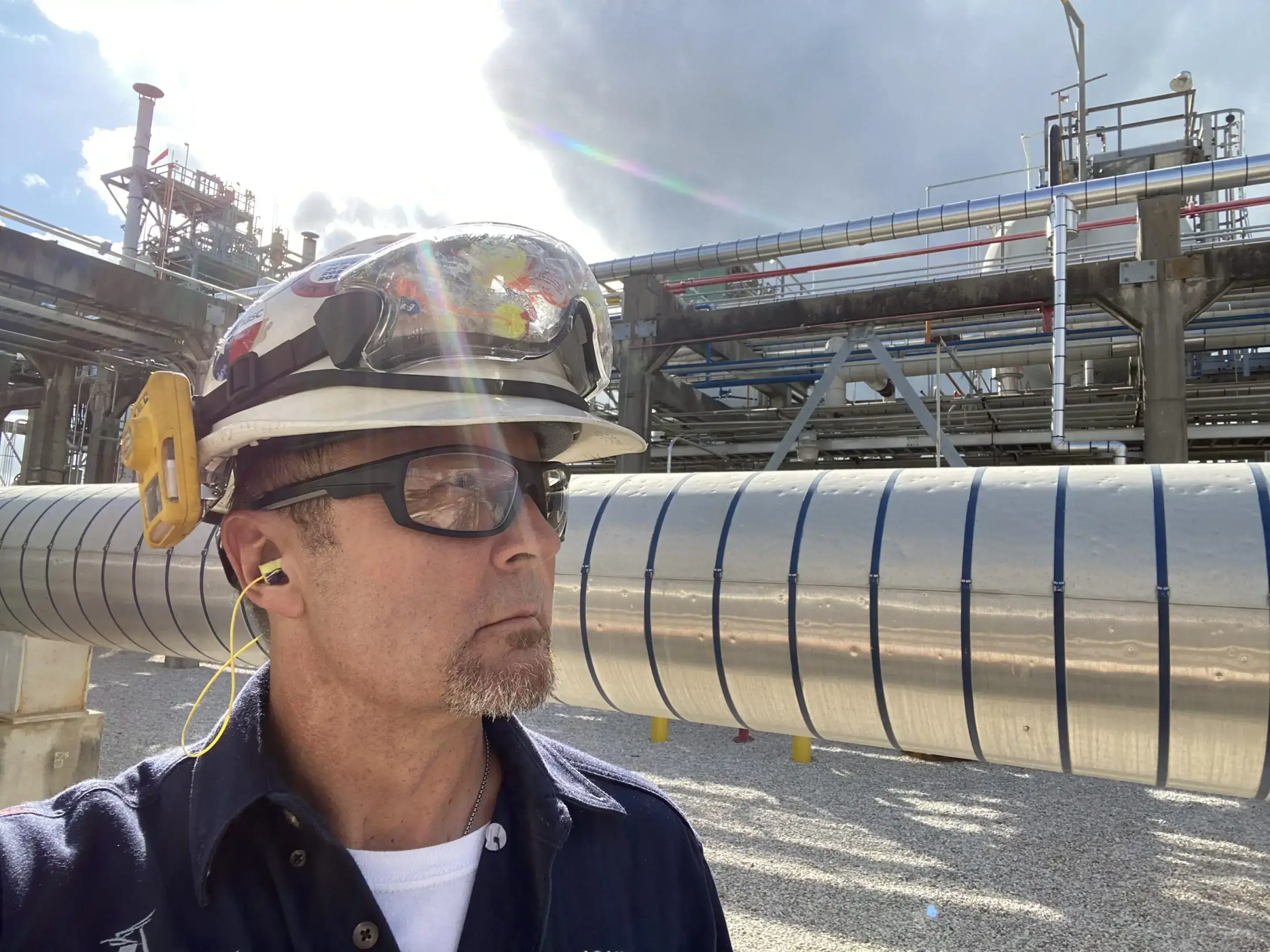 A man wearing a hard hat and glasses.